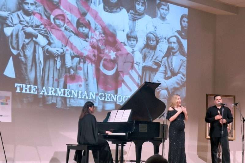 Musical performance at Armenian Genocide memorial event with historical photo projected in background